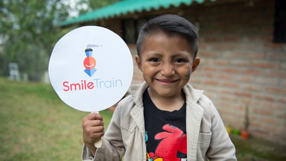 Boy Holding Smile Train Sign 画像提供:スマイルトレイン